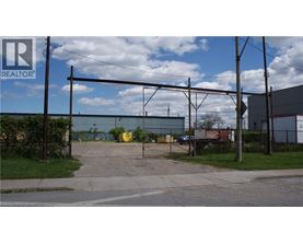 A REALTOR® sign is on a pole in front of a fenced area.