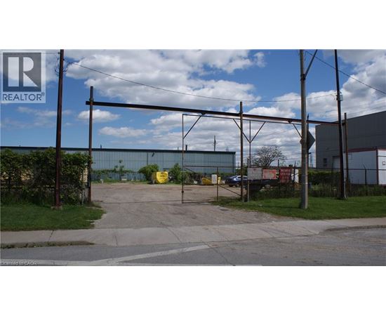 A REALTOR® sign is on a pole in front of a fenced area.