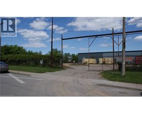 A REALTOR sign is on a pole at the edge of a street.