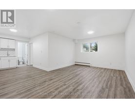 A spacious room with wooden flooring and white walls, with a window showing a snowy landscape outside.