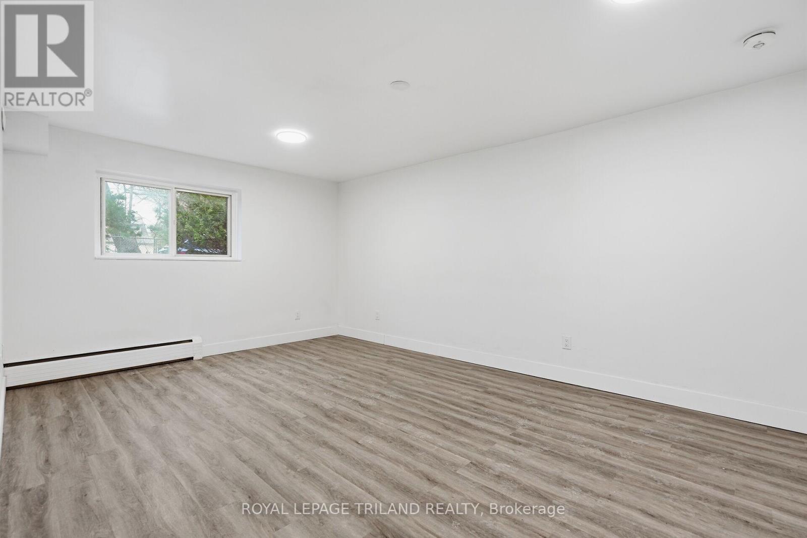 A spacious room with wooden flooring and a window.