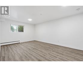 A spacious room with wooden flooring and a window.