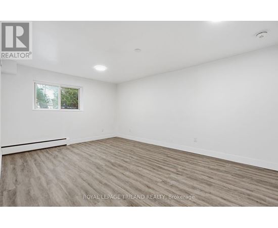A spacious room with wooden flooring and a window.