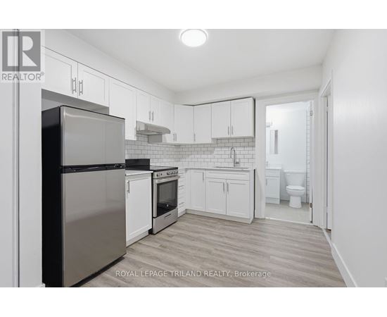 A kitchen with white cabinets and a stainless steel refrigerator.