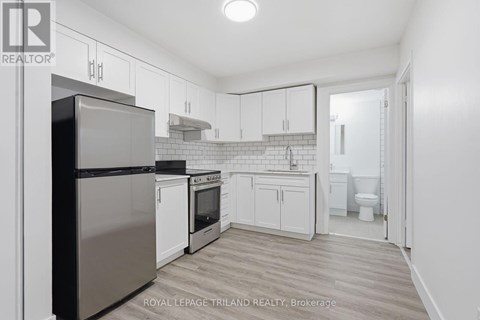 A kitchen with white cabinets and a stainless steel refrigerator.
