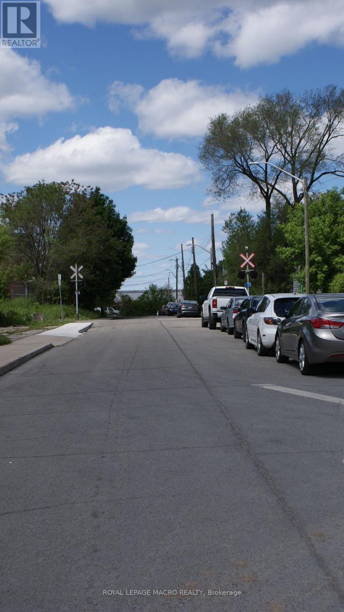 A street with cars parked on the side and a sign for Royal LePage Macro Realty in Brockville.