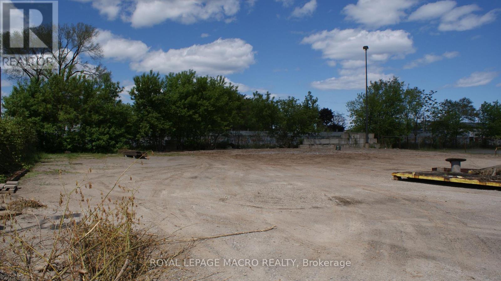 A large, empty parking lot with a sign for Royal LePage Macro Realty in Brockville.