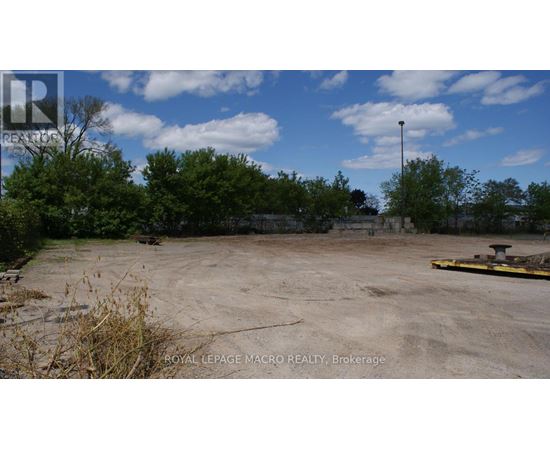 A large, empty parking lot with a sign for Royal LePage Macro Realty in Brockville.