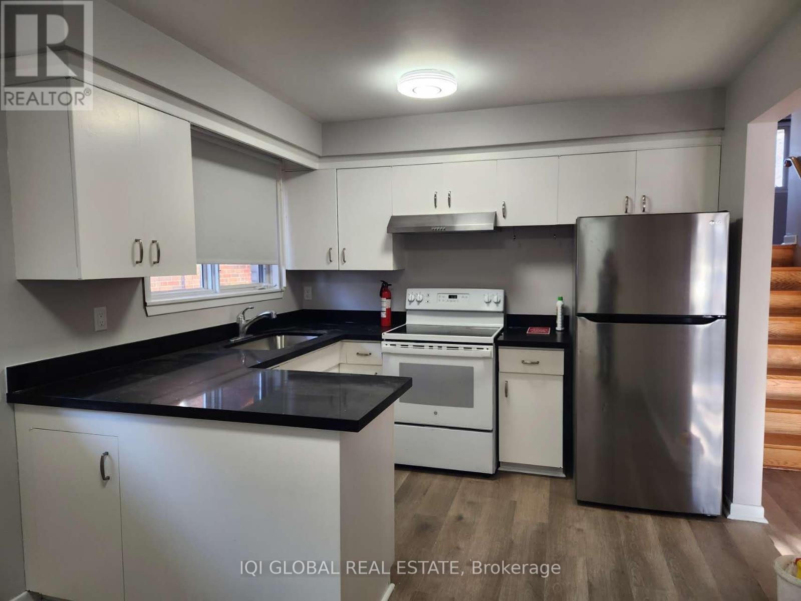 A kitchen with white cabinets and black countertops.