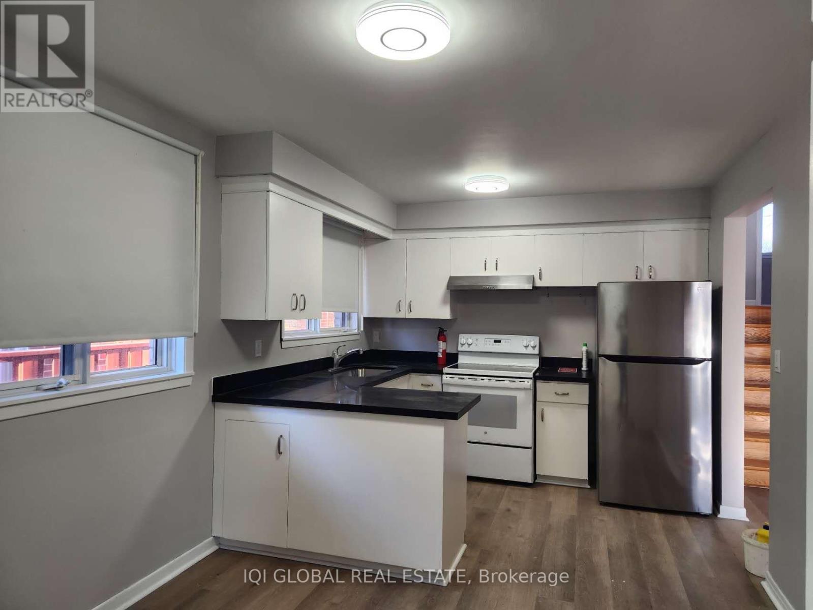 A kitchen with white cabinets and a black countertop.