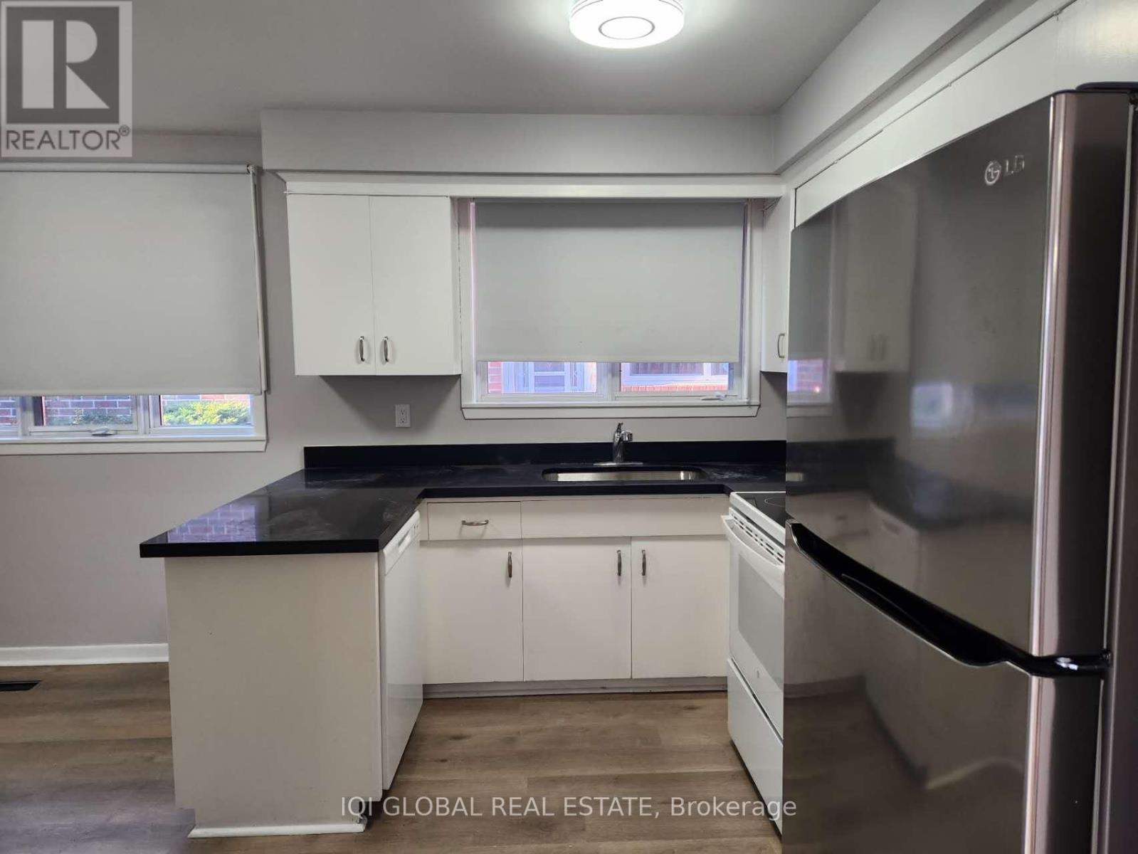 A kitchen with white cabinets and a black countertop.
