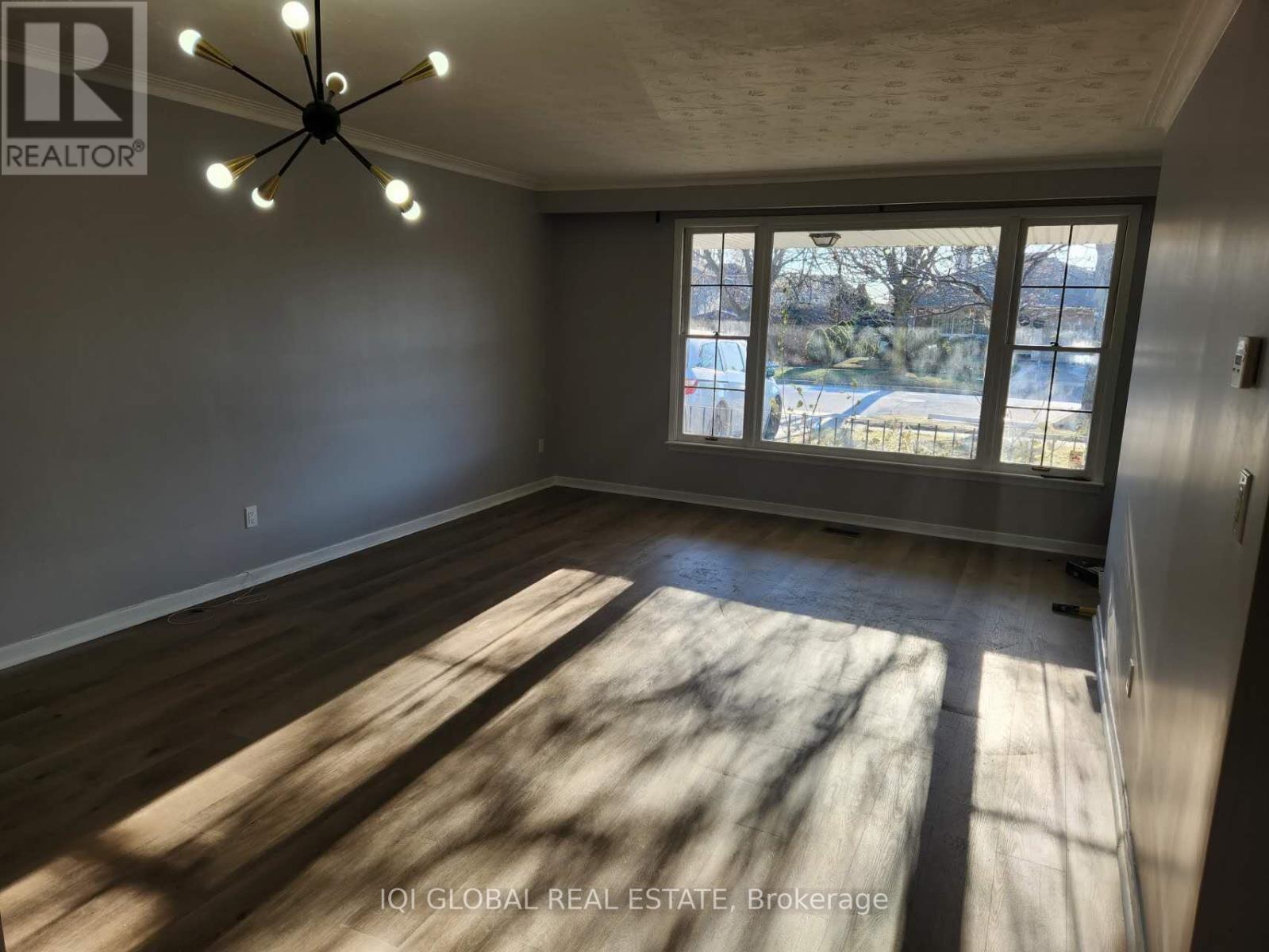 A room with a ceiling fan and a large window letting in sunlight.