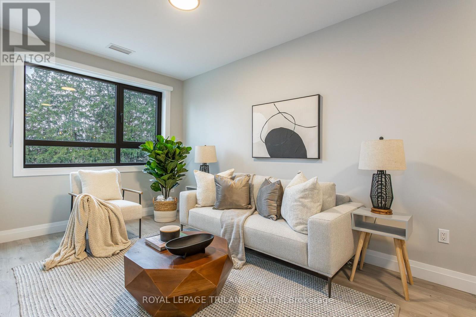 A living room with a white couch, a coffee table, and a large window.