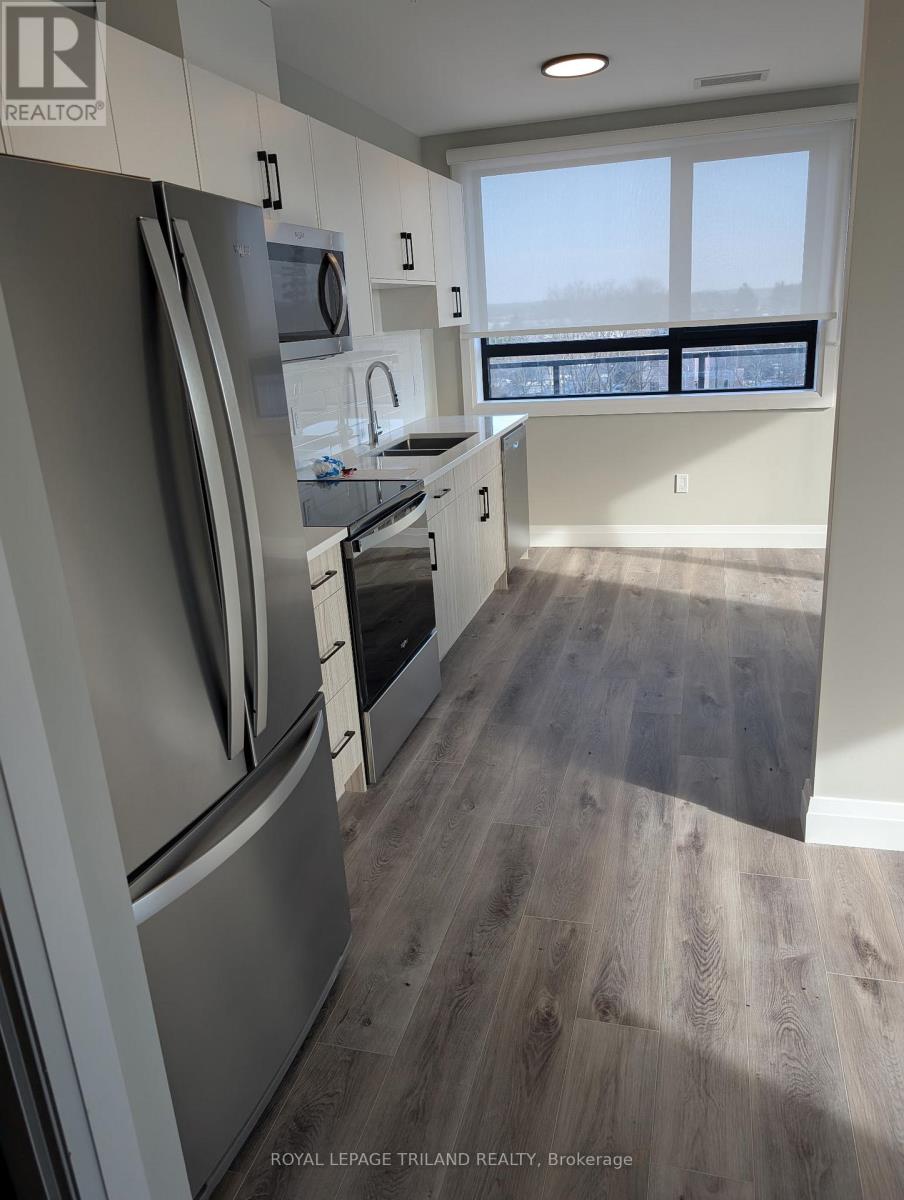 A kitchen with a refrigerator, oven, and sink.