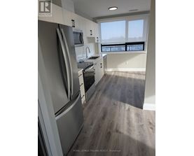 A kitchen with a refrigerator, oven, and sink.