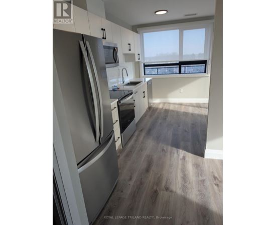 A kitchen with a refrigerator, oven, and sink.