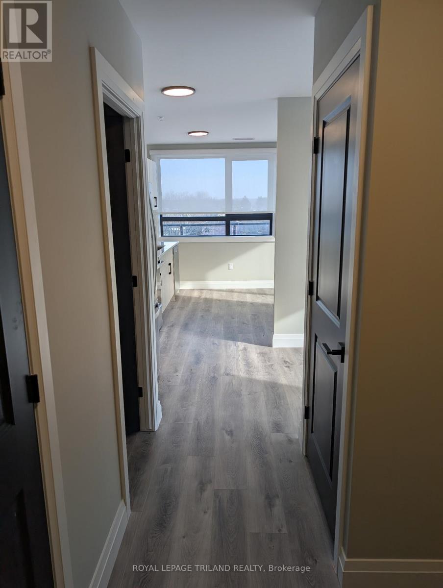 A hallway with a black door and a window in the distance.