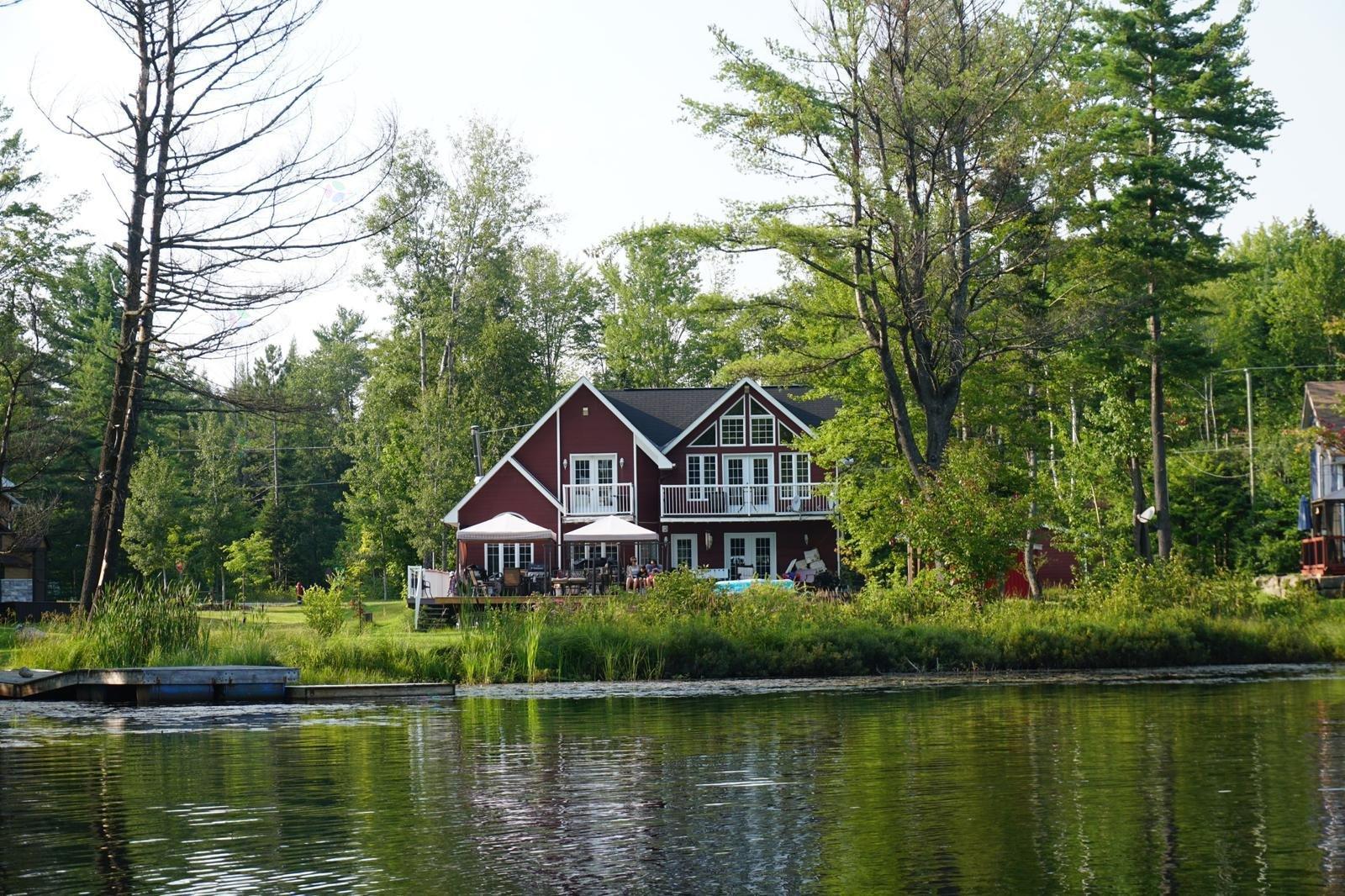 A house with a red roof is situated by a body of water.