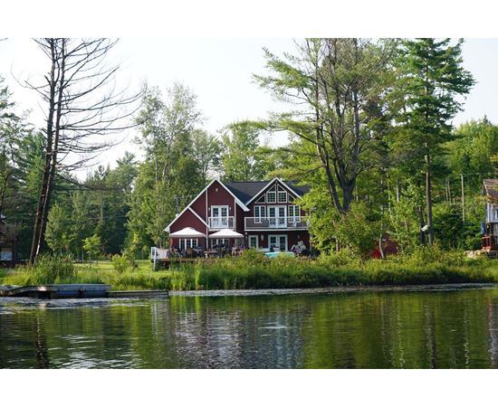 A house with a red roof is situated by a body of water.