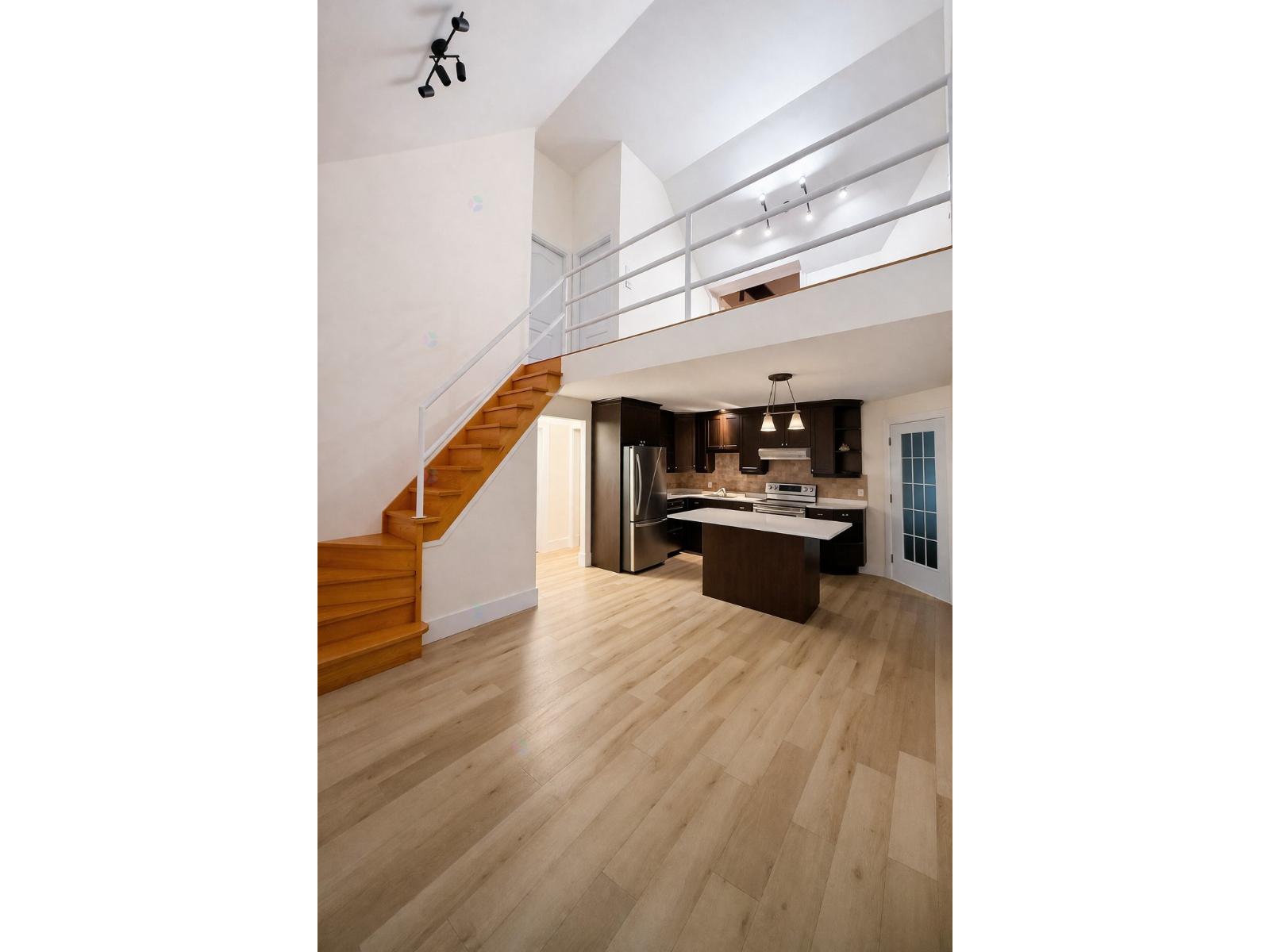 A modern interior with a staircase and a kitchen area.