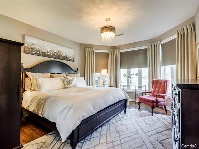 A bedroom with a large bed and a red chair.