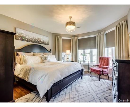 A bedroom with a large bed and a red chair.