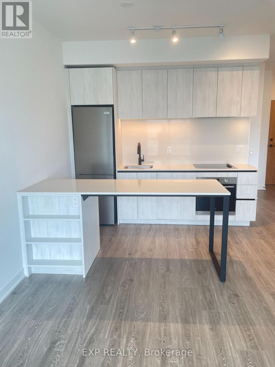 A kitchen with a refrigerator, sink, and a table with drawers.