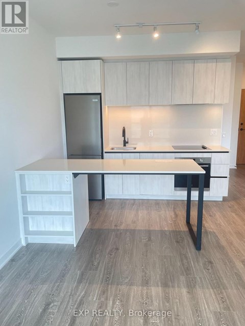 A kitchen with a refrigerator, sink, and a table with drawers.