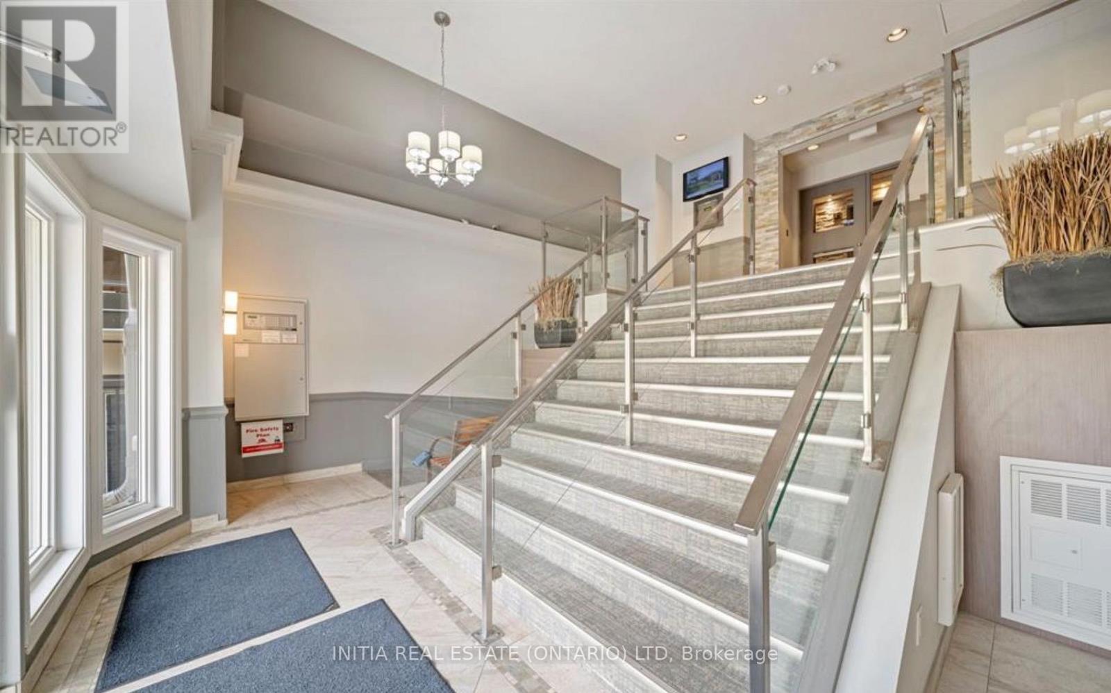 A staircase with a glass railing and a blue carpet on the floor.