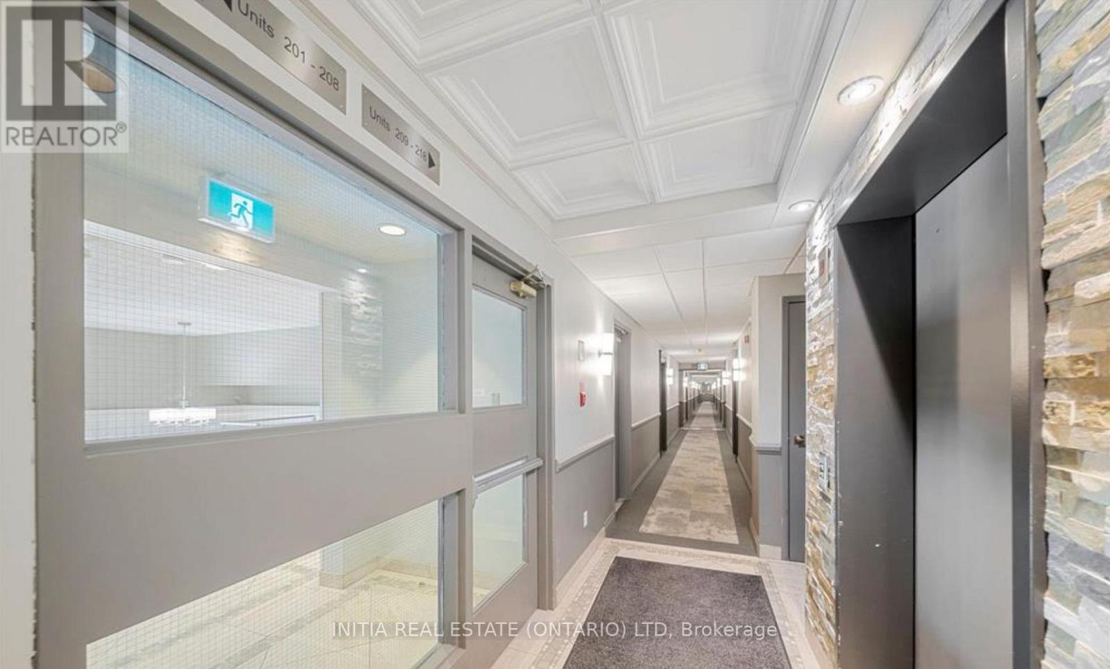 A hallway with a glass door and a brokerage sign.