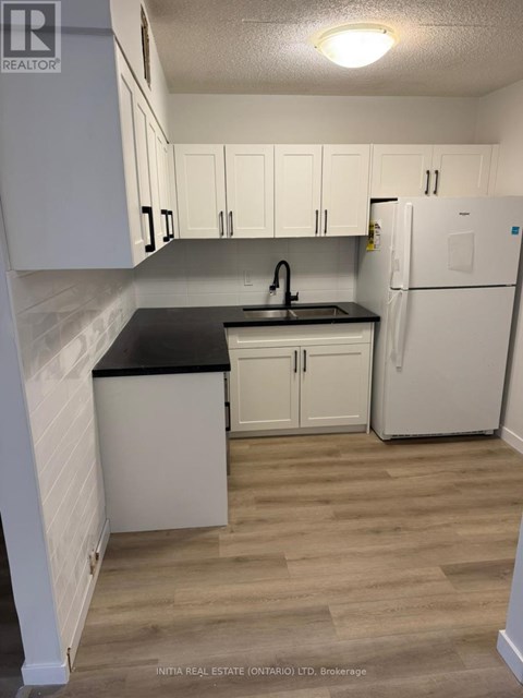 A kitchen with white cabinets and a black countertop.