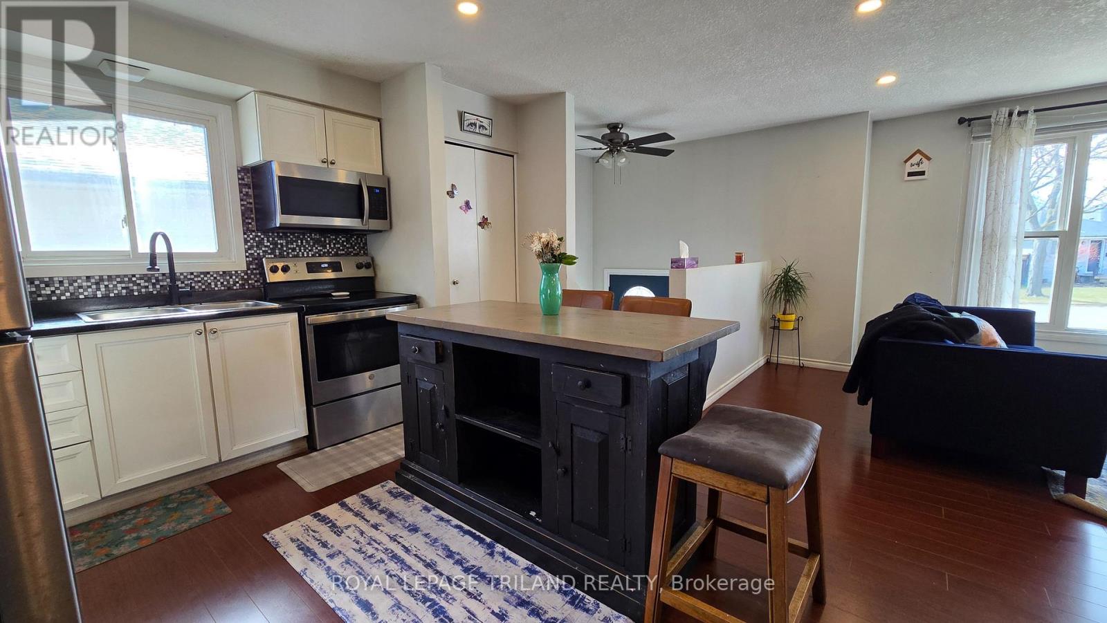 A kitchen with a black stove top oven and a black bar stool.
