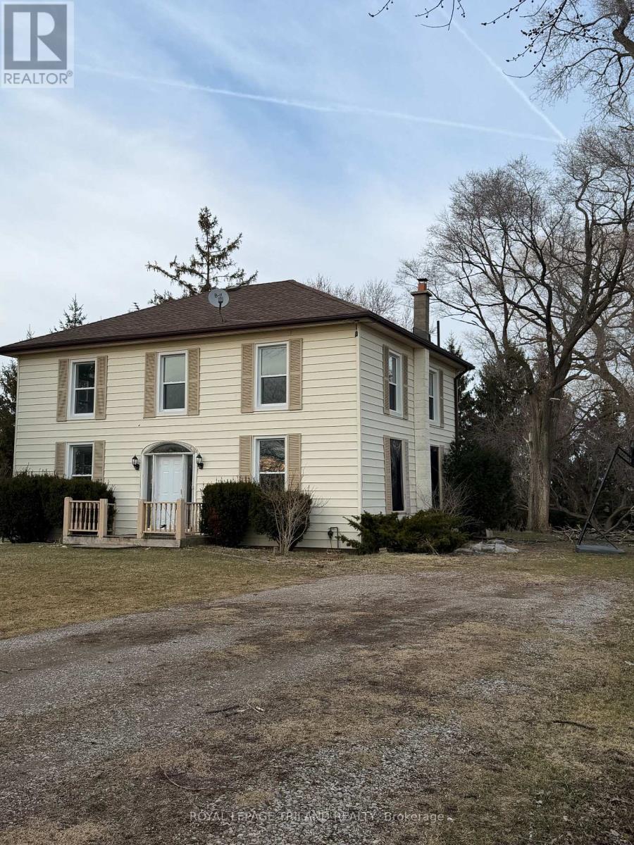 A two-story house with a front porch and a tree in front.