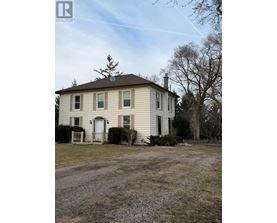 A two-story house with a front porch and a tree in front.