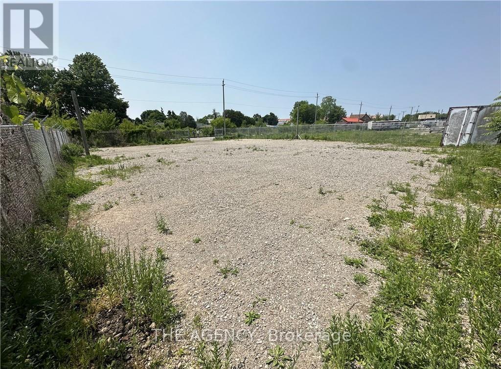 A gravel lot with a fence and greenery in the background.