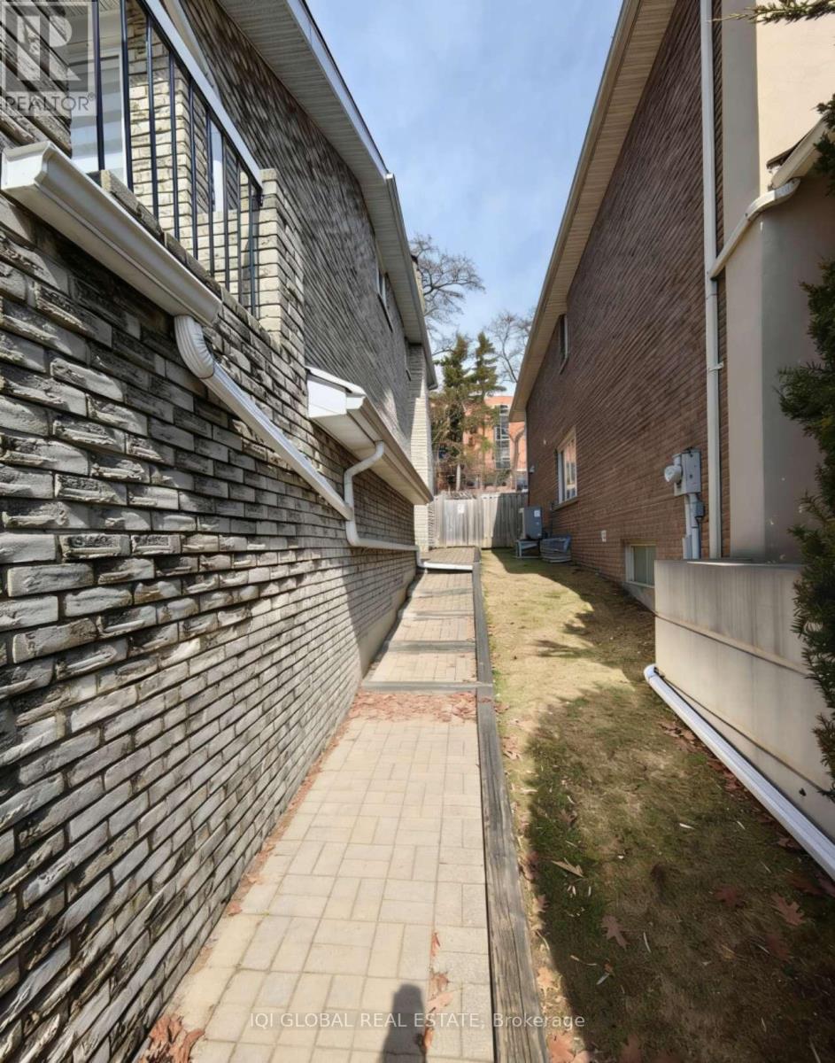 A narrow alley with a brick wall on one side and a grassy area on the other.