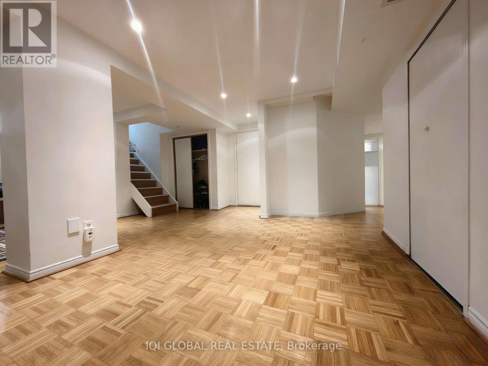 A spacious room with wooden flooring and white walls.
