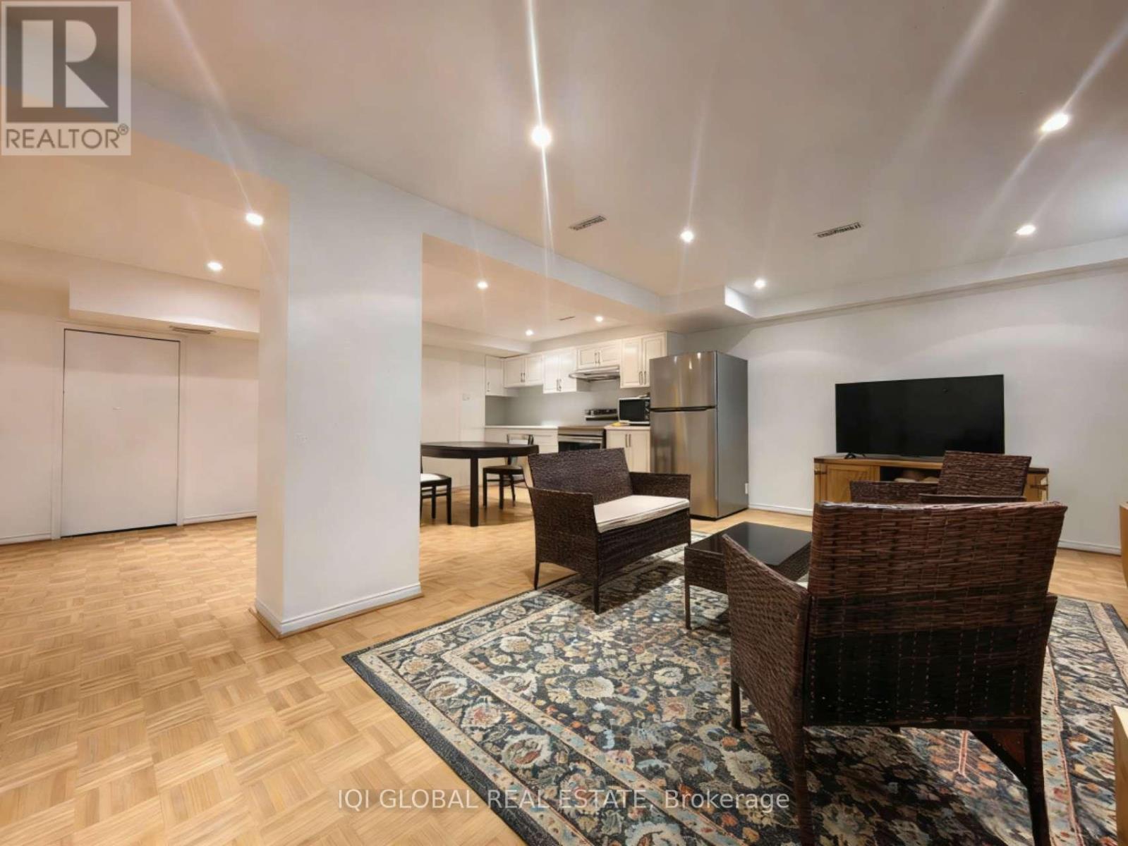 A living room with a couch, chairs, and a rug.