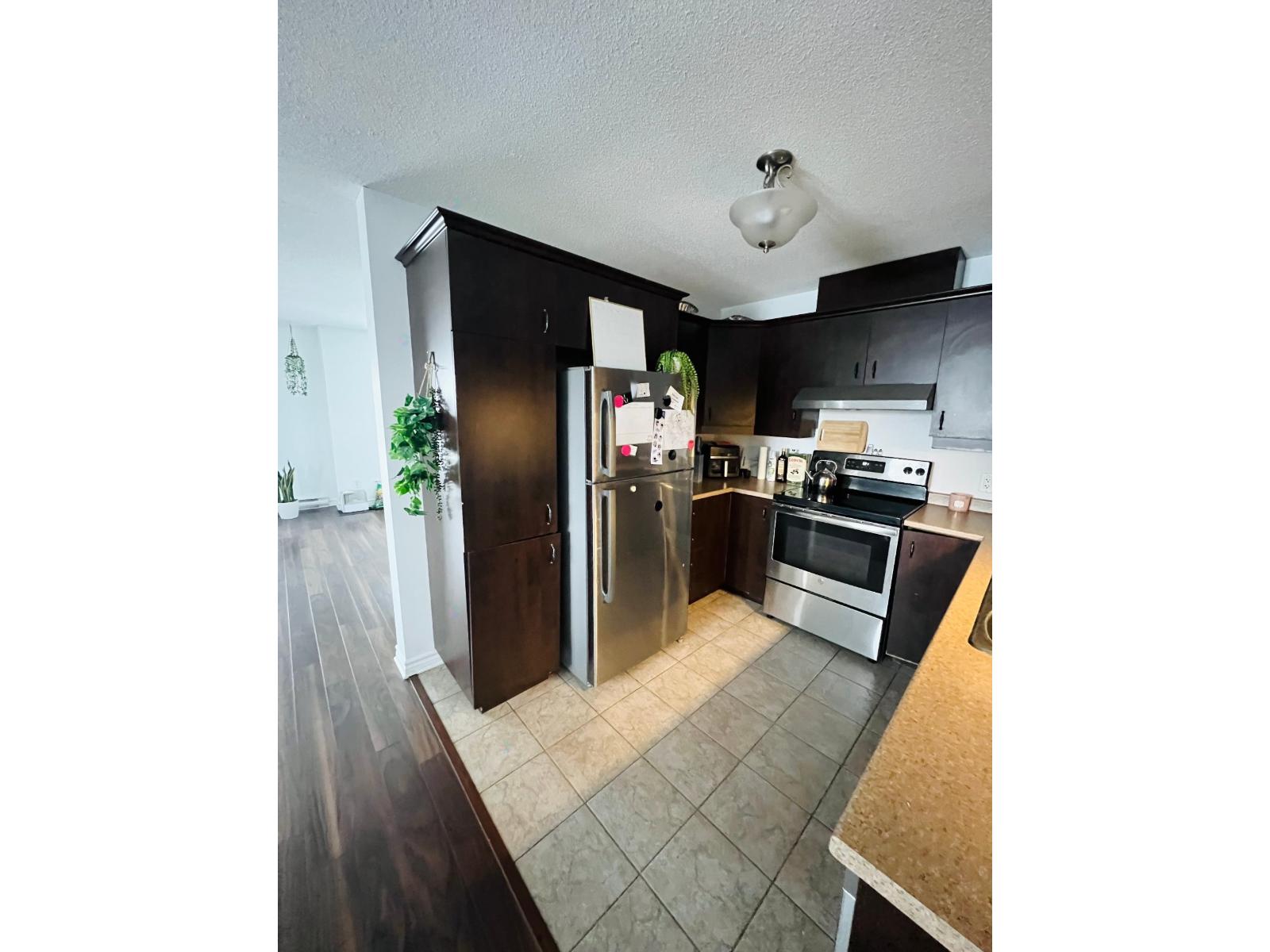 A kitchen with a refrigerator, microwave, and oven.