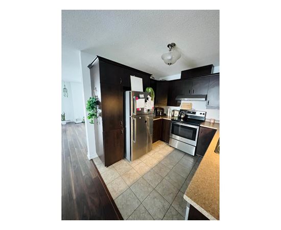 A kitchen with a refrigerator, microwave, and oven.