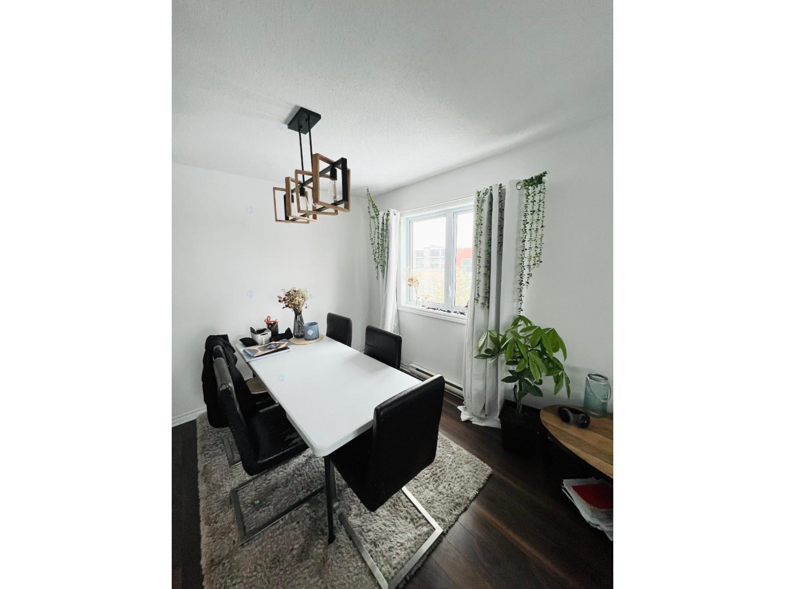 A dining room with a white table and black chairs.