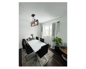 A dining room with a white table and black chairs.