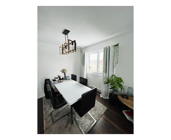 A dining room with a white table and black chairs.