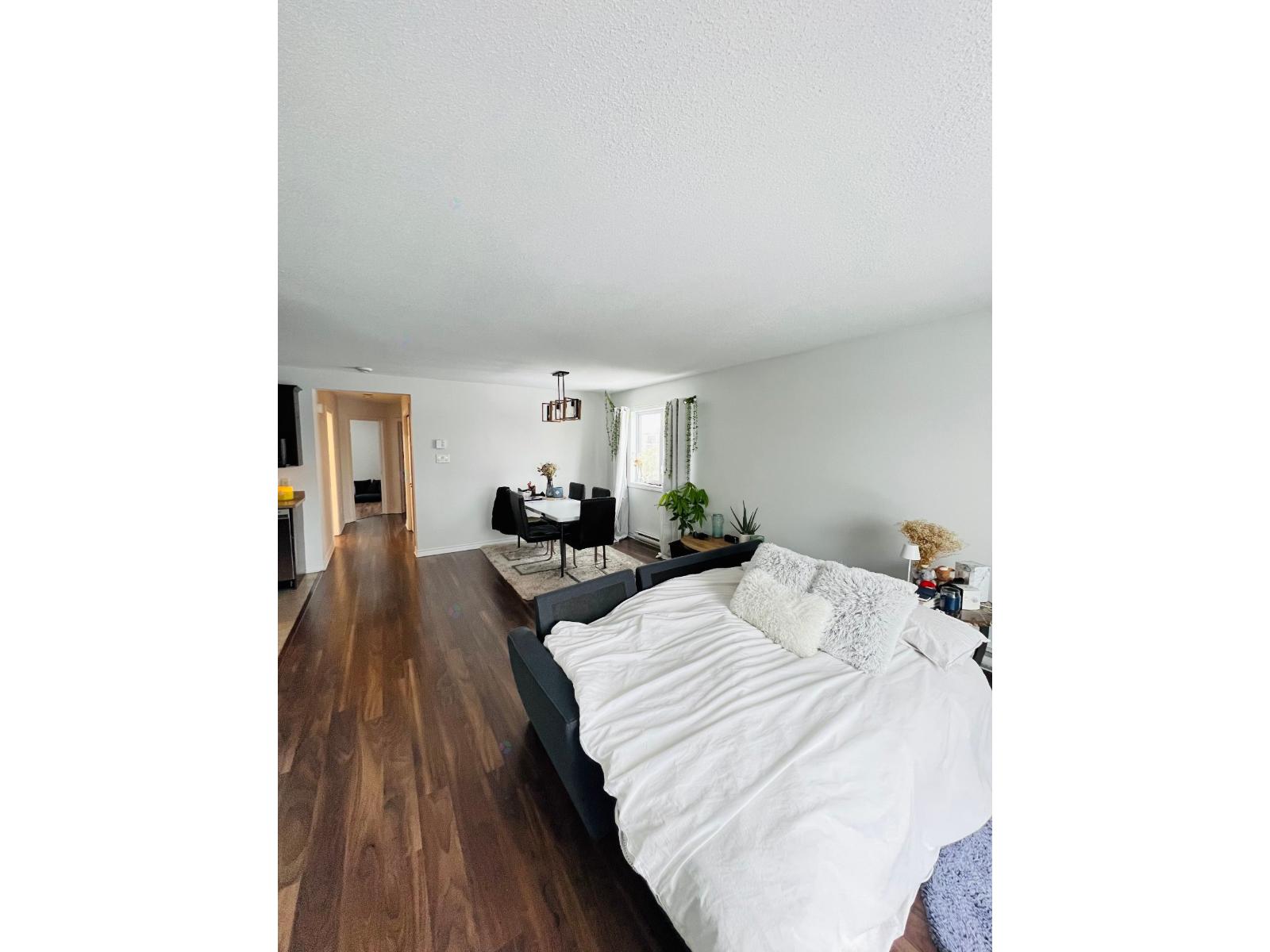 A bedroom with a large bed and a wooden floor.
