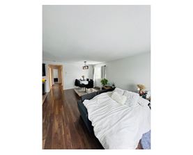 A bedroom with a large bed and a wooden floor.