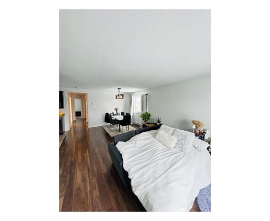 A bedroom with a large bed and a wooden floor.