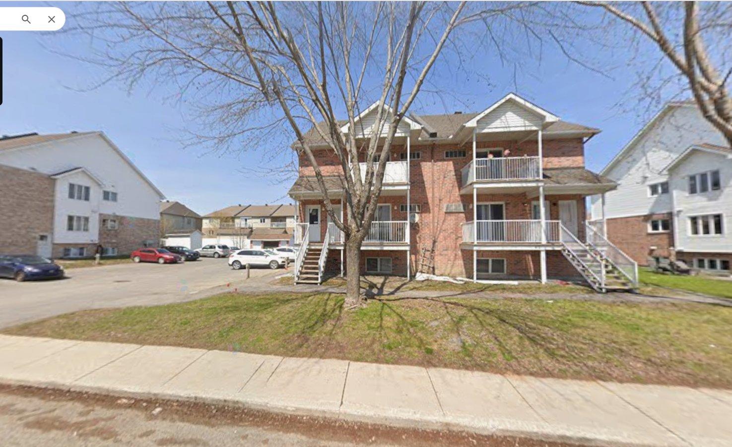 A street view of a residential area with houses and cars.