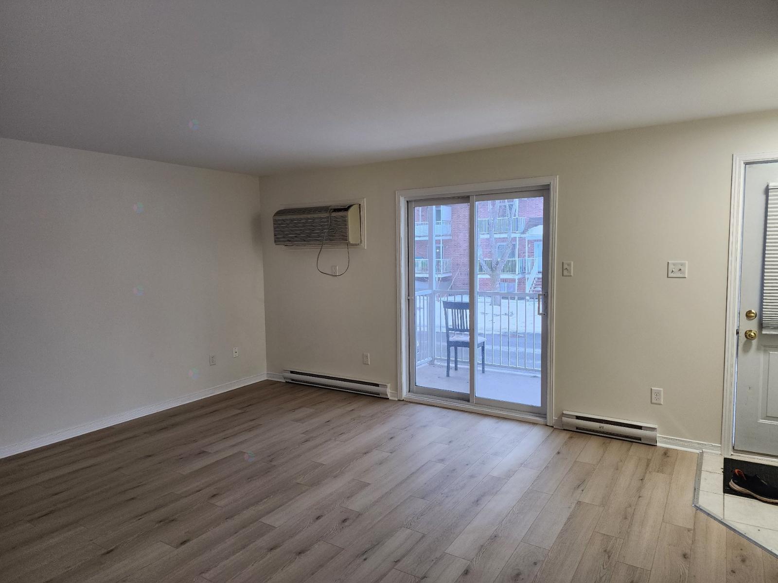 A room with a sliding glass door leading to a balcony.