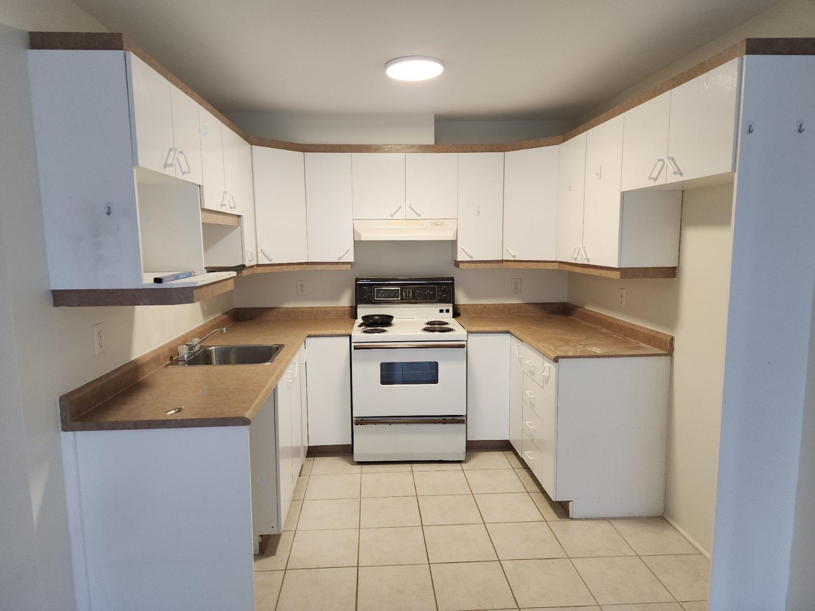 A kitchen with white cabinets and a stove top oven.