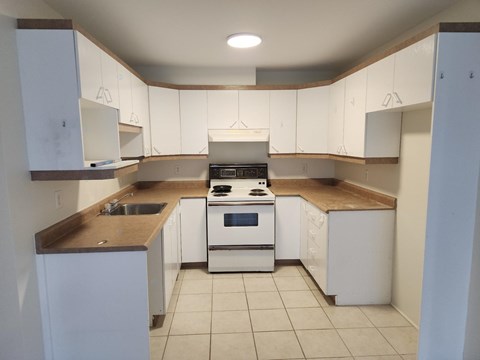 A kitchen with white cabinets and a stove top oven.